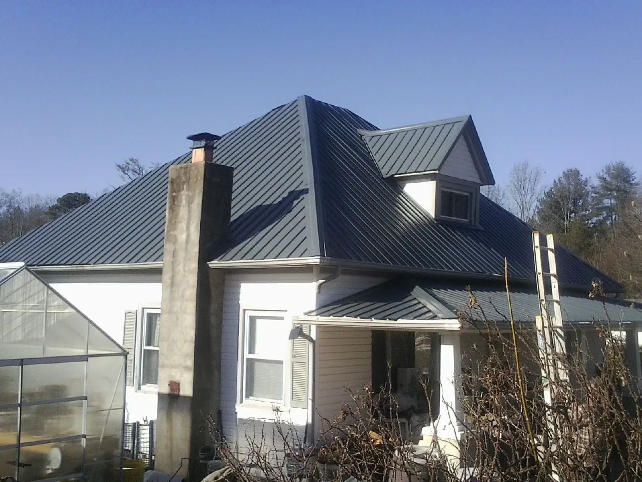 Dark blue standing seam metal roof on a white farmhouse with dormer — Slate & Tile Roof Repair by Roofing Brothers in Whiteville