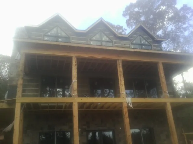 Dormers and porch framing on a large log home under construction — Roof Coating work by our crew in Whiteville