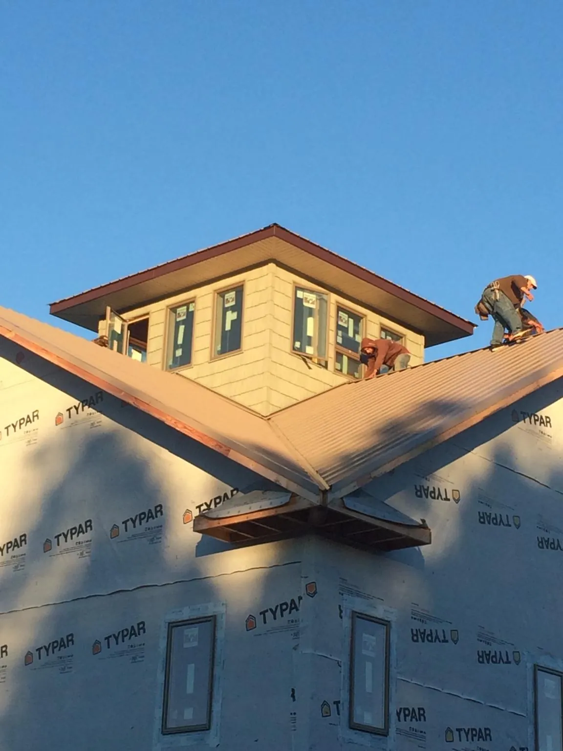 Roofers working around a rooftop cupola on a new metal roof at sunset — Roof Waterproofing in Whiteville by Roofing Brothers